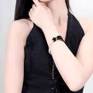 Bracelet perlé noir avec nœud central délicat porté au poignet féminin, style élégant et contemporain.