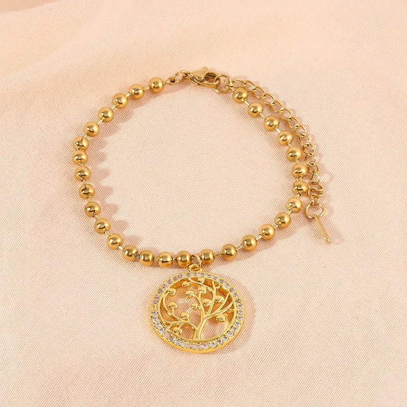 Bracelet perlé en titane doré avec pendentif arbre de vie orné de pierres blanches.