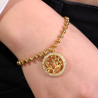 Bracelet perlé en titane doré avec pendentif arbre de vie ajouré pour femme.