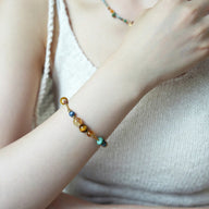 Bracelet perlé multicolore avec pierres naturelles et perles dorées sur poignet féminin, style élégant et délicat.