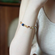 Bracelet perlé multicolore avec pierres naturelles rondes et éclats dorés sur poignet féminin, style élégant et délicat.