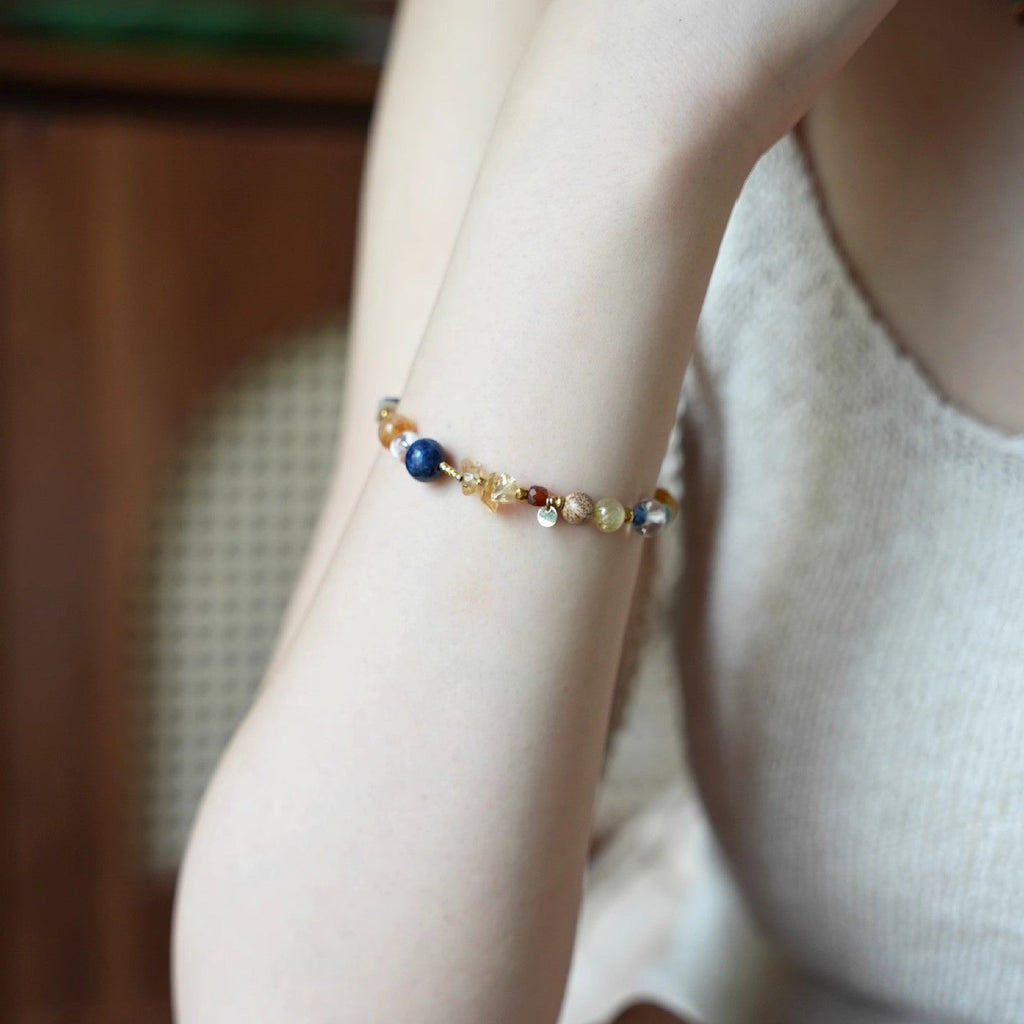 Bracelet perlé multicolore avec pierres naturelles rondes et éclats dorés sur poignet féminin, style élégant et délicat.