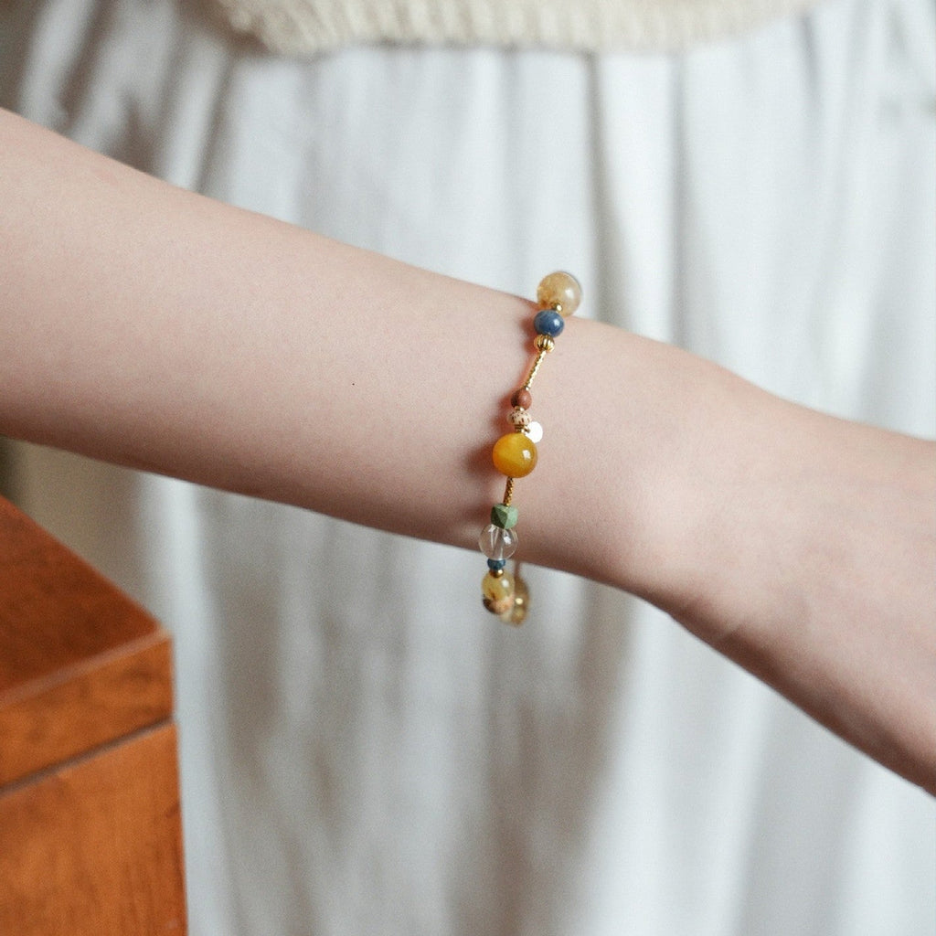 Bracelet perlé multicolore avec pierres naturelles rondes, détails dorés et lien fin ajustable, style élégant et délicat.