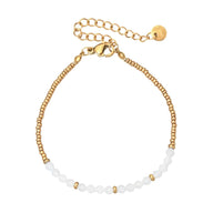 Bracelet fin en perles blanches nacrées et petites perles dorées, fermoir mousqueton doré avec chaîne de réglage.