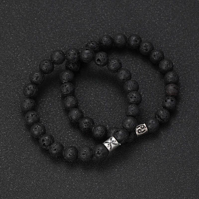 Bracelet élastique perles noires en pierre de lave avec deux breloques métal argenté aux symboles astrologiques du zodiaque.