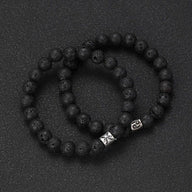 Bracelet élastique perles noires en pierre de lave avec deux breloques métal argenté aux symboles astrologiques du zodiaque.