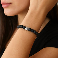 Bracelet élastique en perles noires de pierre de lave avec carré métallique argenté gravé symbole astrologique Lion.