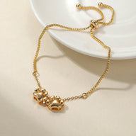 Bracelet mixte en acier inoxydable or avec pendentifs pattes réglable par chaîne coulissante.