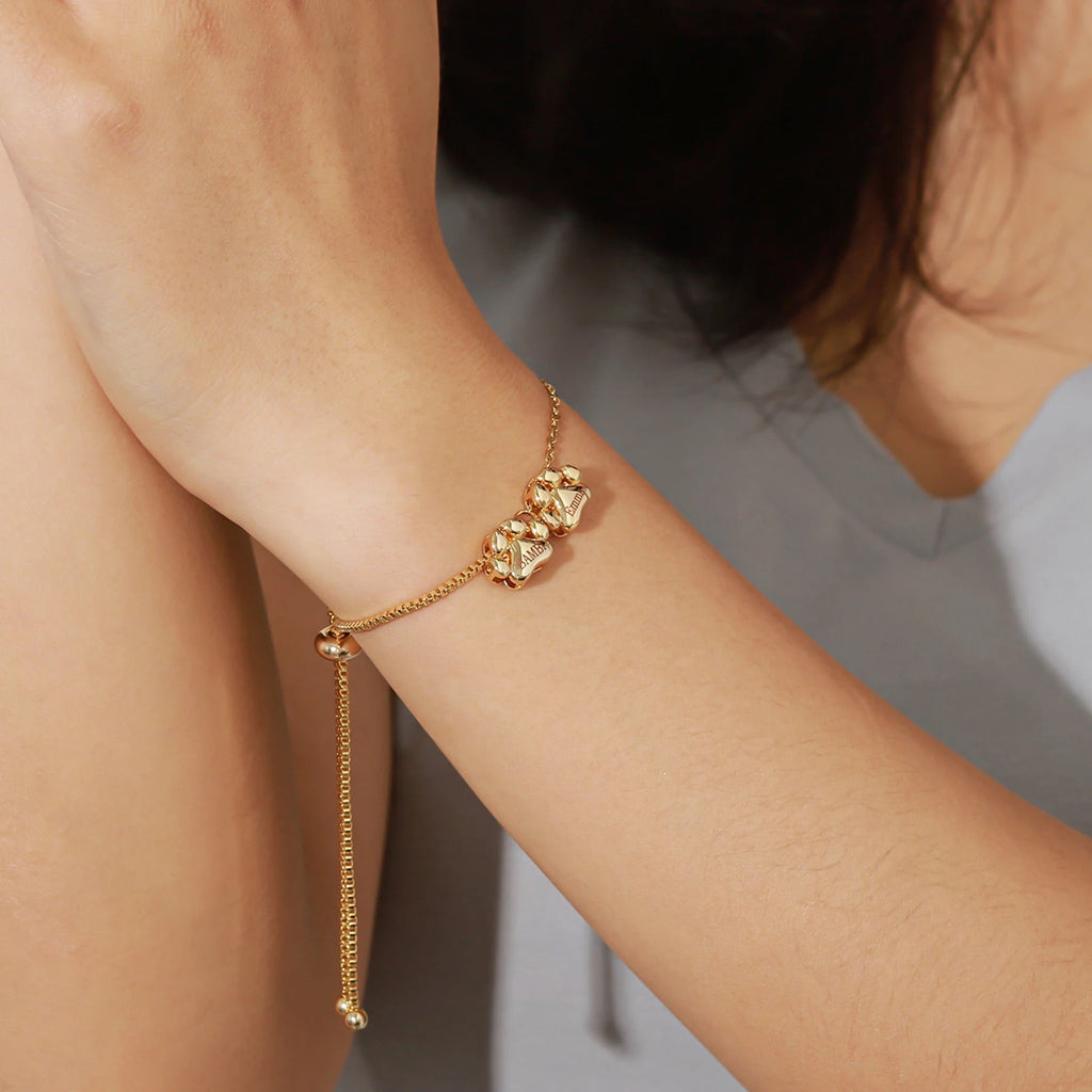 Bracelet fin en acier inoxydable or avec pendentifs hexagonaux délicats porté au poignet.