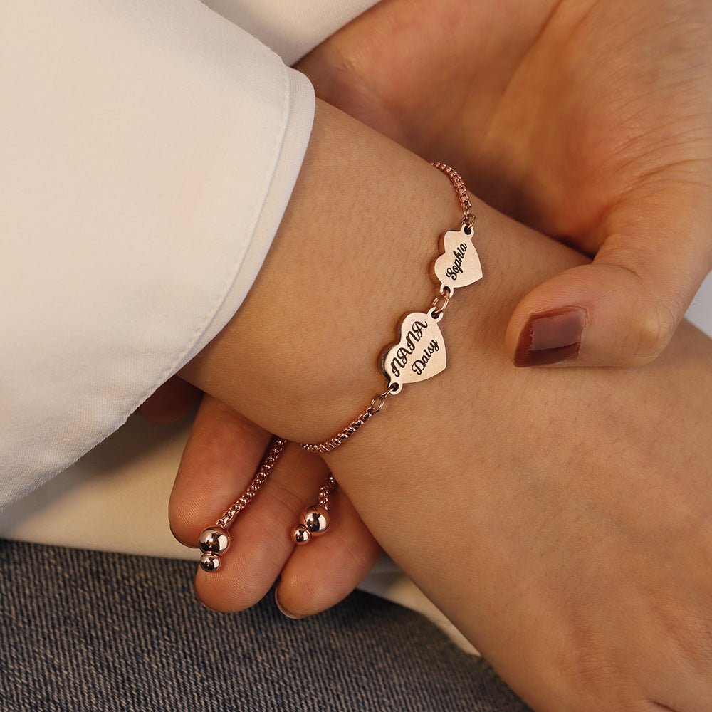 Bracelet ajustable en acier inoxydable rose avec cœurs gravés de prénoms, design délicat et moderne.