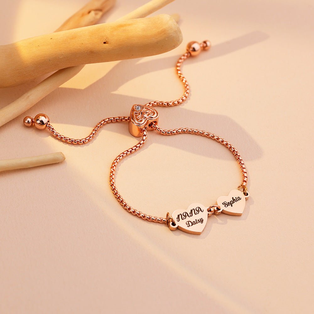 Bracelet ajustable en acier inoxydable rose doré avec deux cœurs gravés de prénoms, chaîne coulissante fine.