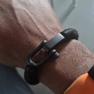 Bracelet homme noir à mousqueton mat avec lien en corde tressée et fermoir robuste.