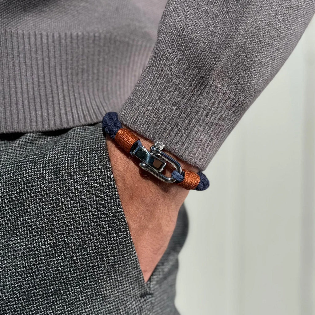 Bracelet homme bleu marine en corde tressée avec fermoir mousqueton argenté porté au poignet.