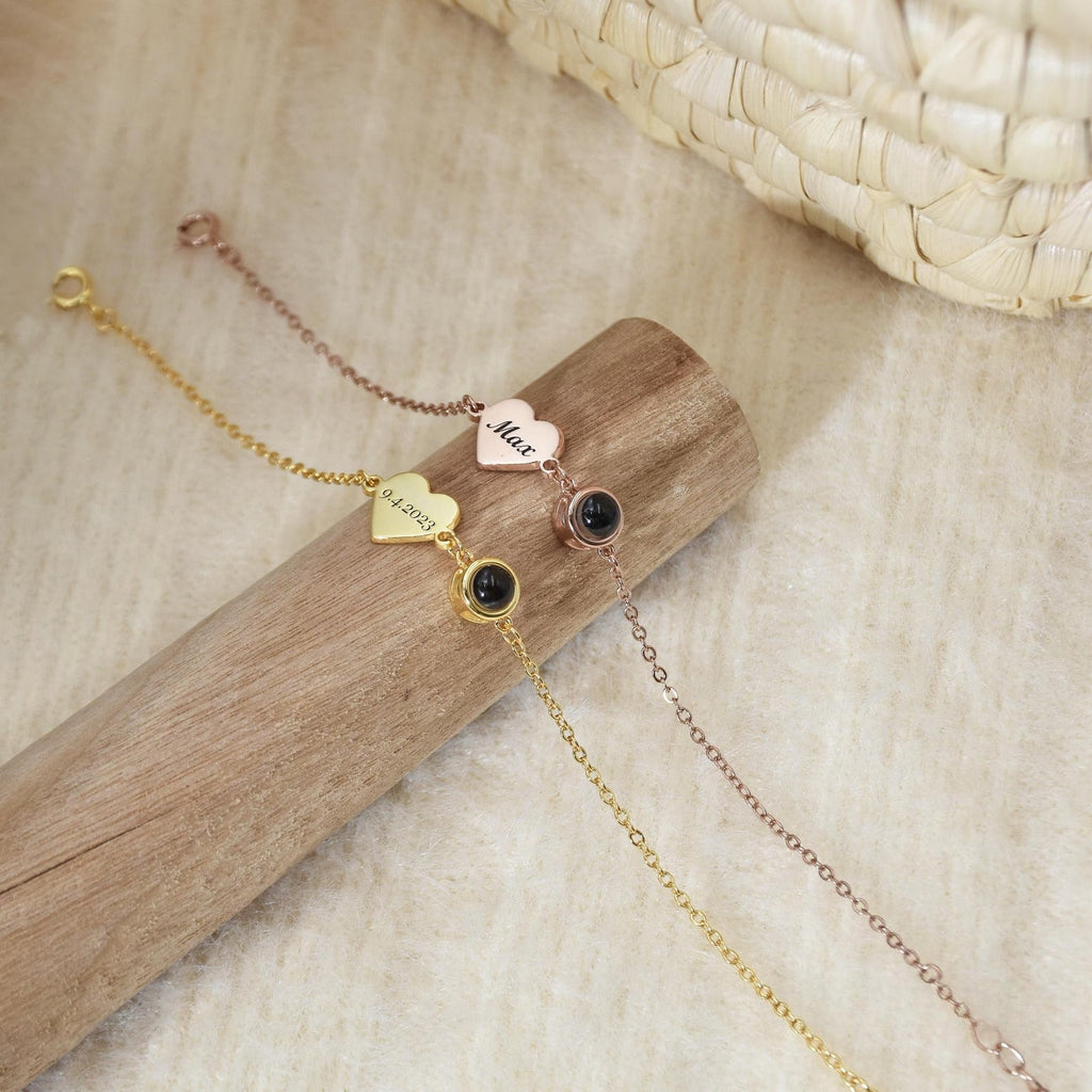 Trois bracelets fins en acier inoxydable or et rose, avec pendentifs cœur gravés et un motif noir rond sur chaîne délicate.