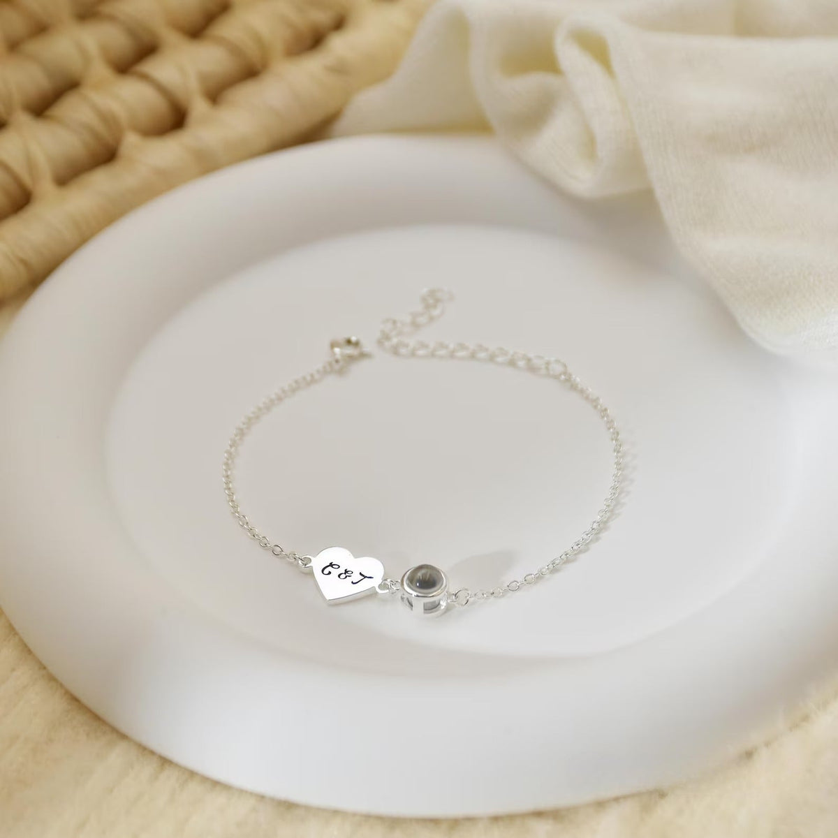 Bracelet fin en acier inoxydable avec pendentif cœur gravé et médaille ronde noire, style délicat et élégant.