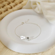 Bracelet fin en acier inoxydable avec pendentif cœur gravé et médaille ronde noire, style délicat et élégant.