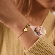 Bracelet fin en acier inoxydable doré avec pendentif cœur gravé et médaillon photo personnalisable.