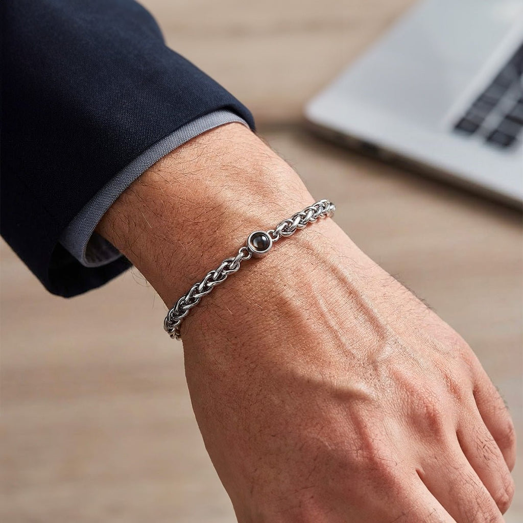 Bracelet maille tressée en acier inoxydable argenté avec fermoir réglable porté au poignet masculin.