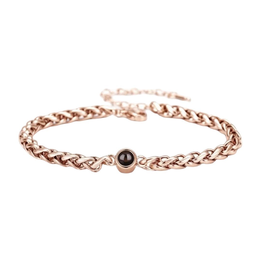 Bracelet maille tressée en acier inoxydable couleur or rose avec perle noire centrale et fermoir réglable.