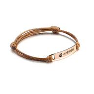 Bracelet cordon marron avec plaque en acier inoxydable or rosé gravée motif Spotify.