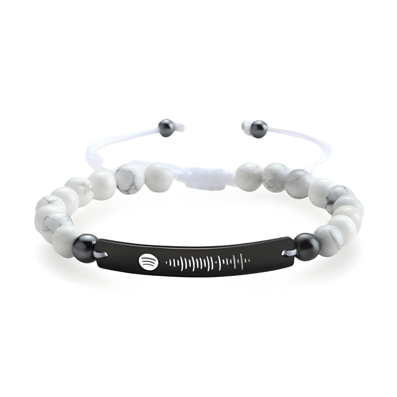 Bracelet personnalisé Spotify en pierres naturelles blanches avec plaque noire gravée et cordon ajustable blanc.
