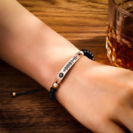 Bracelet personnalisé Spotify noir avec pierres naturelles et plaque argent gravée sur un poignet.