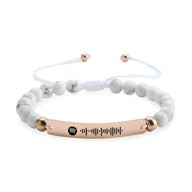 Bracelet personnalisé blanc en pierres naturelles avec plaque or rosé gravée d'un code Spotify.