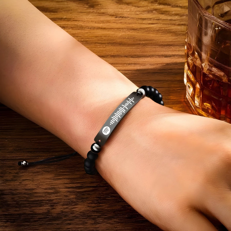 Bracelet personnalisé Spotify en pierres noires avec plaque argentée gravée style moderne sur poignet.