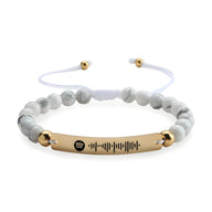 Bracelet personnalisé Spotify en pierres naturelles blanches avec plaque dorée rosée et cordon ajustable blanc.