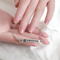 Bracelet gourmette argent ajustable avec plaque gravée code Spotify portée au poignet féminin.