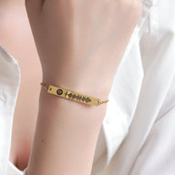 Bracelet gourmette ajustable en or jaune avec gravure code Spotify, porté au poignet.