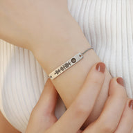 Bracelet gourmette argenté ajustable avec code Spotify gravé et chaîne fine sur poignet féminin.