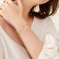 Bracelet jonc en acier inoxydable or rose avec gravure personnalisée style Spotify porté au poignet féminin.