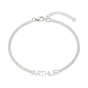 Bracelet fin en acier inoxydable argenté avec prénom "ARTHUR" en lettres découpées, chaîne maille cubaine et fermoir.