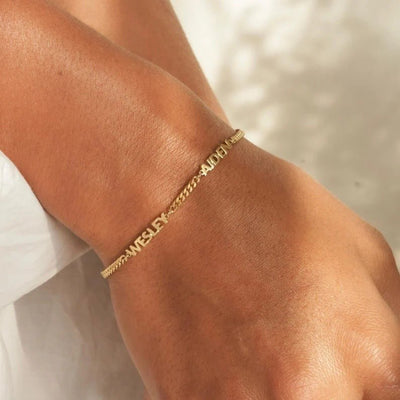 Bracelet fin en acier inoxydable doré avec trois prénoms taillés en maille cubaine élégante.