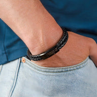 Bracelet double tour en cuir tressé noir avec fermoir en métal argenté gravé.