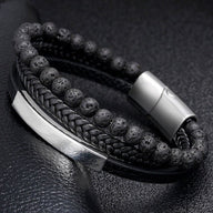 Bracelet homme multi-rangs noir avec perles volcaniques, cuir tressé, plaque métallique argentée et fermoir magnétique.