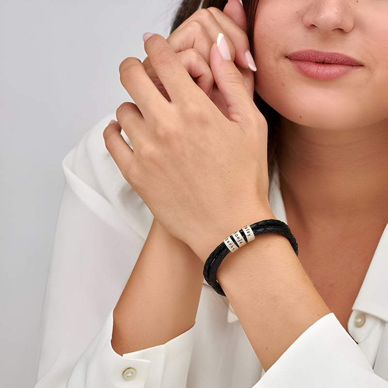 Bracelet triple tour en cuir noir avec trois anneaux gravables en acier inoxydable porté au poignet.