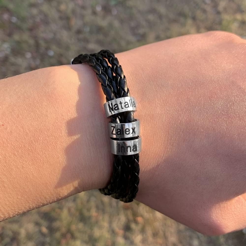 Bracelet triple tour en cuir noir tressé avec trois anneaux métalliques gravés de prénoms.