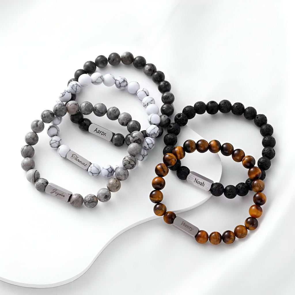 Lot de bracelets naturels mixtes en pierre volcanique, jaspe gris et œil de tigre avec étiquettes noires et blanches.