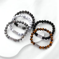 Lot de bracelets naturels mixtes en pierre volcanique, jaspe gris et œil de tigre avec étiquettes noires et blanches.