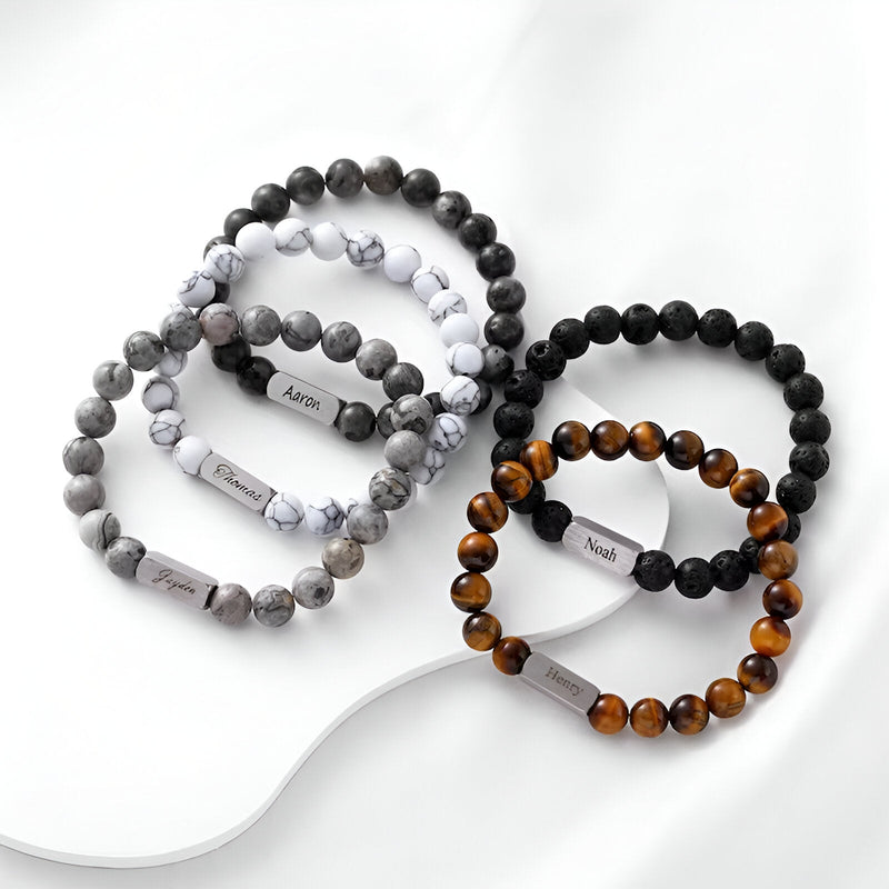 Lot de bracelets naturels mixtes en pierre volcanique, jaspe gris et œil de tigre avec étiquettes noires et blanches.