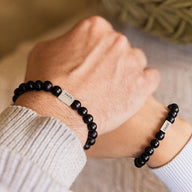 Bracelet mixte en perles noires mate avec plaque argentée gravée ZOHAR, style naturel et épuré.