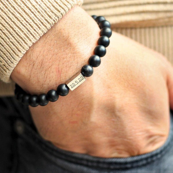 Bracelet mixte en perles noires mates avec plaque gravée en métal argenté.