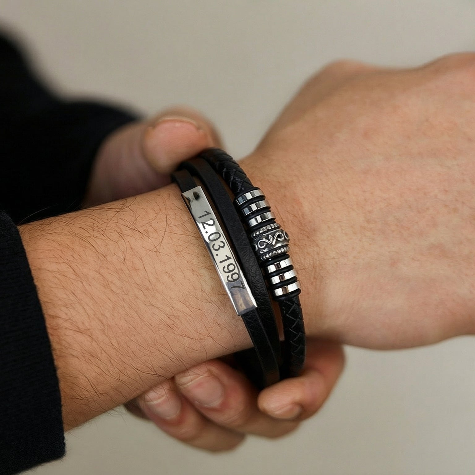 Bracelet homme en simili cuir noir avec plaque gravée et fermoir aimanté argenté, style moderne et épuré.