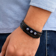 Bracelet cuir noir multi-rangs avec trois yeux protecteurs bleus et fermoir magnétique, style moderne.