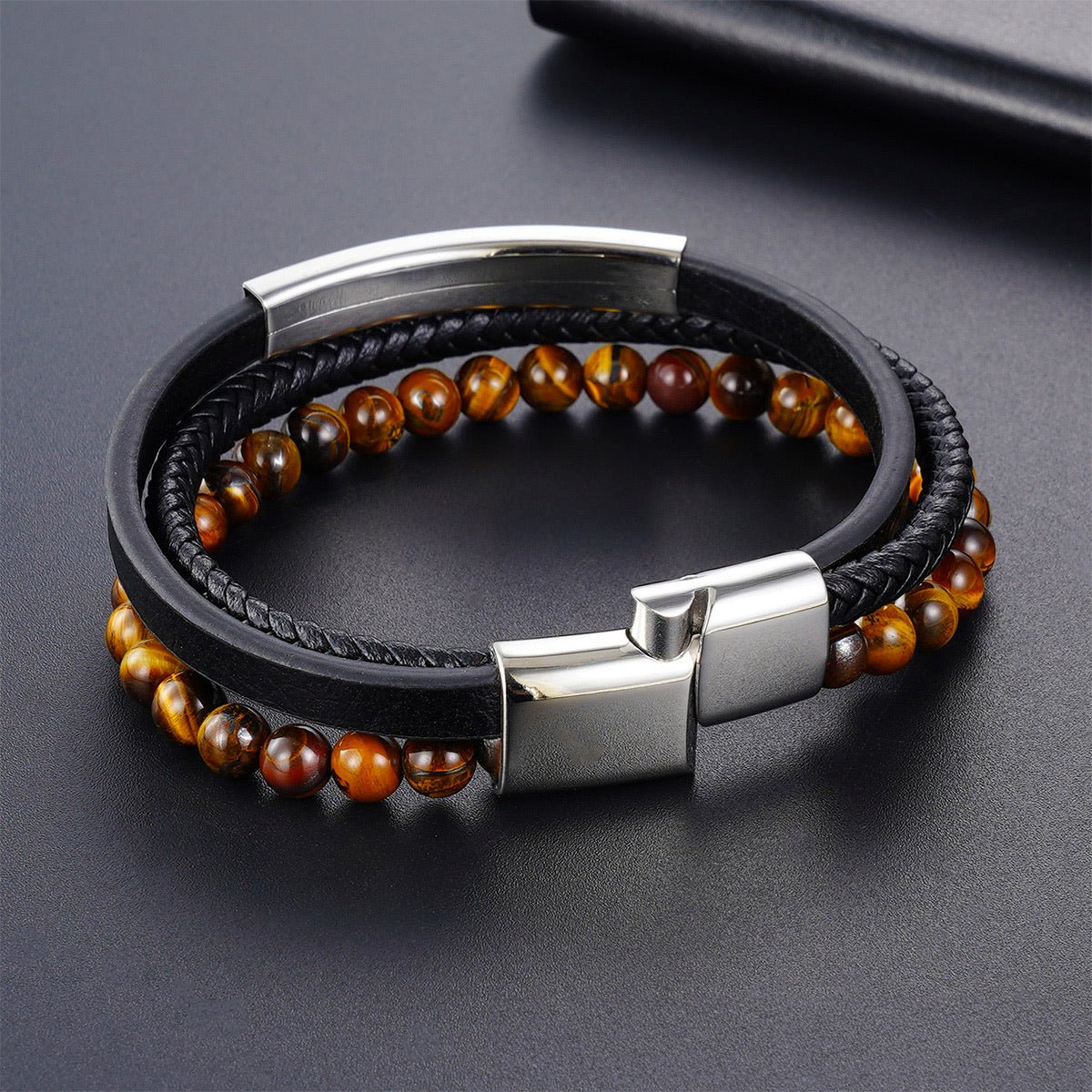 Bracelet homme en cuir noir tressé avec perles naturelles œil de tigre marron et fermoir magnétique acier inoxydable élégant.