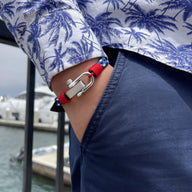 Bracelet homme rouge avec mousqueton en acier inoxydable sur poignet, style décontracté élégant.