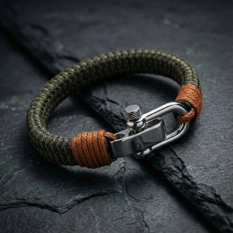 Bracelet homme en coton vert kaki tressé avec fermoir manille en acier inoxydable et détails en cuir marron.