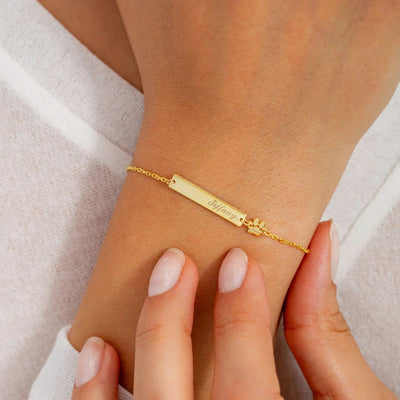 Bracelet fin en acier inoxydable doré avec plaque gravée et chaîne à maillons délicats.